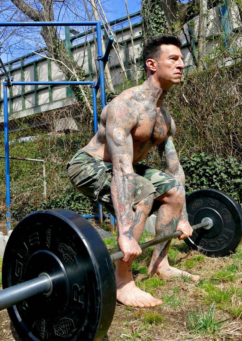 Danny Kavadlo, author of Hybrid Strength Training performing barbell deadlifts in his backyard