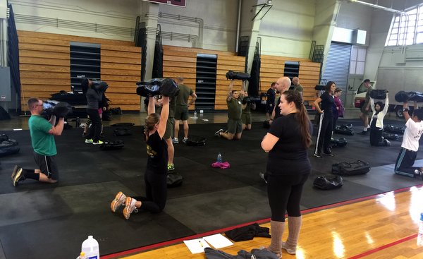 Faith Martin leading a class in Ultimate Sandbag kneeling overhead press